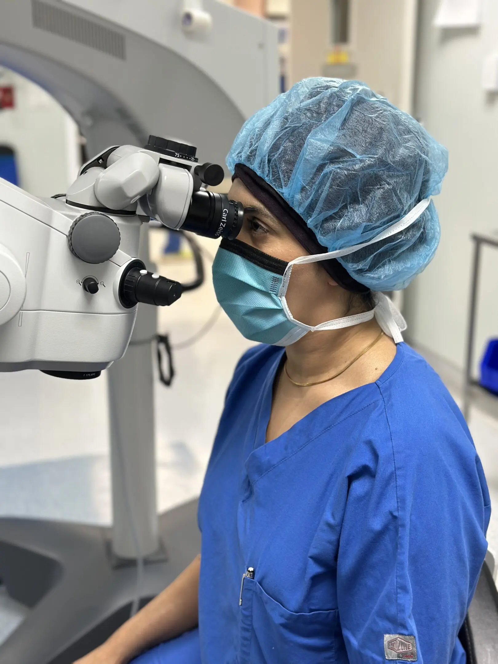 HK microscope 2 A woman in blue scrubs looking into an ophthalmoscope.